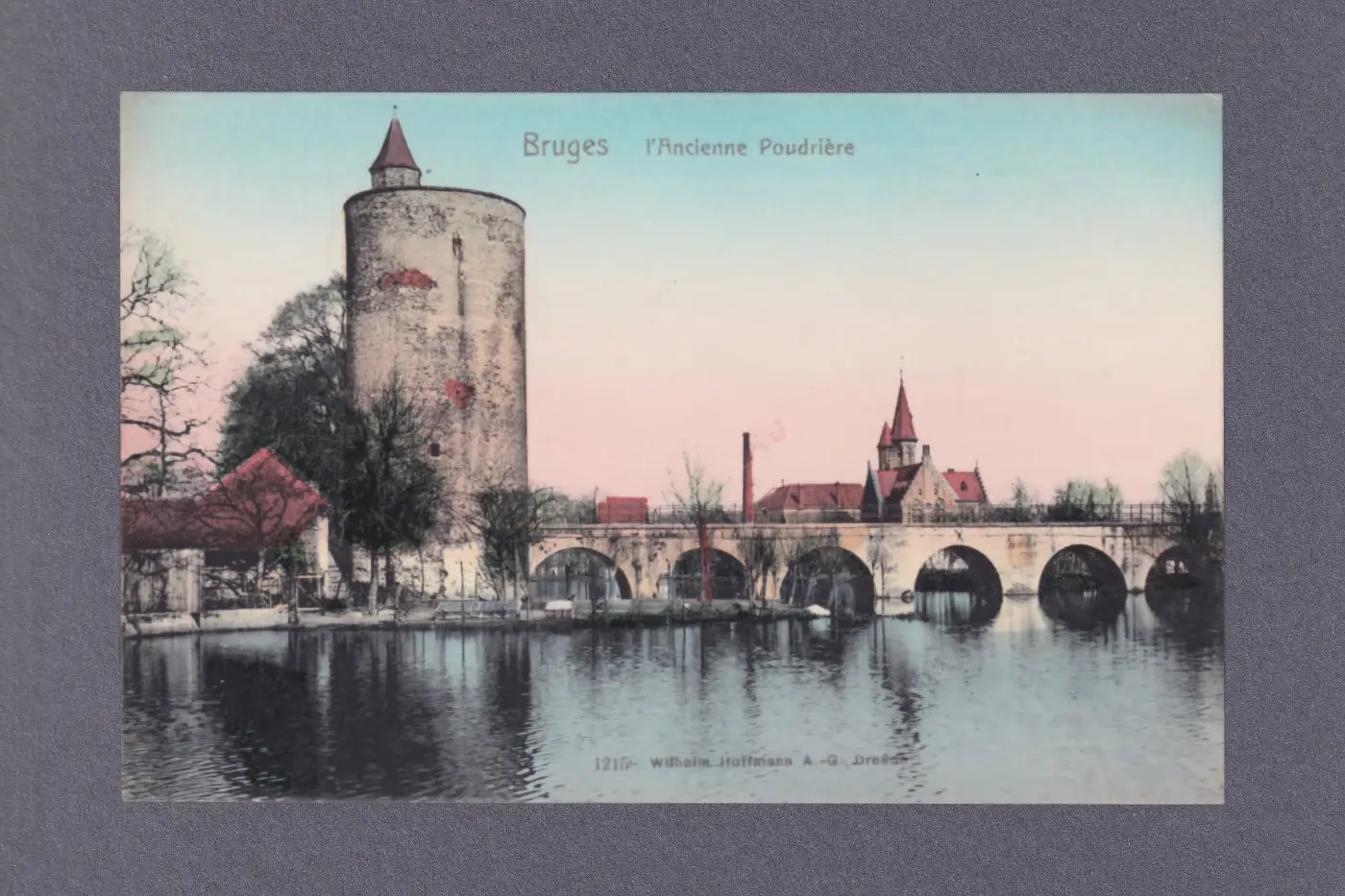 A colour-tinted postcard showing an old stone tower and bridge over a river in Bruges.